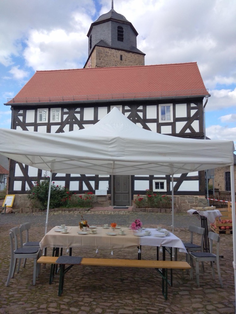 Gedeckte Kaffeetafel unter einem Pavillon vor der Wehrdaer Fachwerkkirche