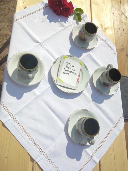 Kaffeetafel im Freien mit Kärtchen „Schön, dass wir Nachbarn sind.